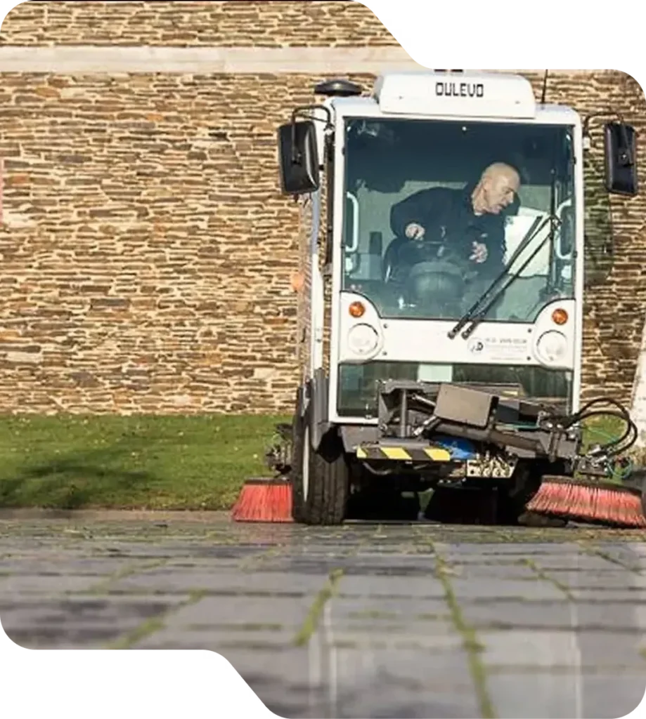 Veegmachine reinigt het terrein van een bedrijfspand